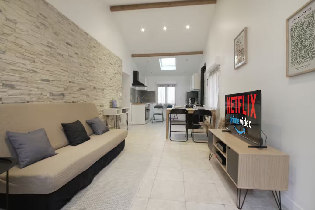 Séjour lumineux avec canapé-lit et mur en pierre